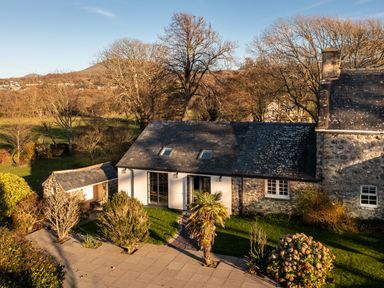 A stone house with slate roof surrounded by trees and shrubs at Bennar Fawr in Dyffryn Ardudwy