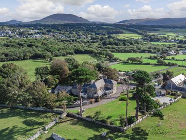 A countryside property with stone buildings surrounded by green fields and trees at Bennar Fawr in Dyffryn Ardudwy