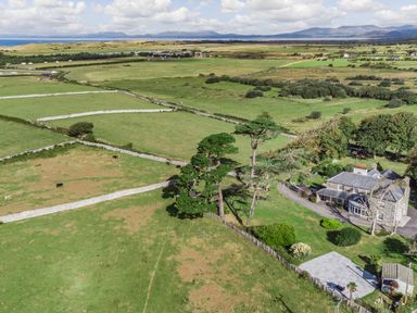 A rural landscape with divided green fields cows trees and a house at Bennar Fawr in Dyffryn Ardudwy