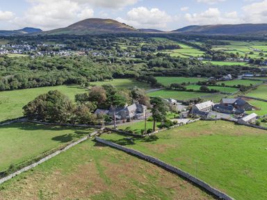 A rural landscape with stone buildings and green fields surrounded by stone walls at Bennar Fawr in Dyffryn Ardudwy