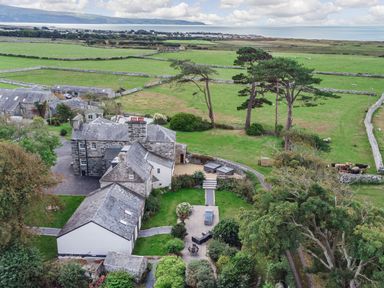 A countryside property with stone houses surrounded by green fields and trees at Bennar Fawr in Dyffryn Ardudwy