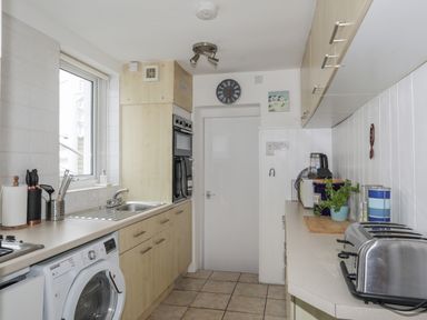 A kitchen with a washing machine sink toaster and countertop appliances at Awel Y Mor in Criccieth