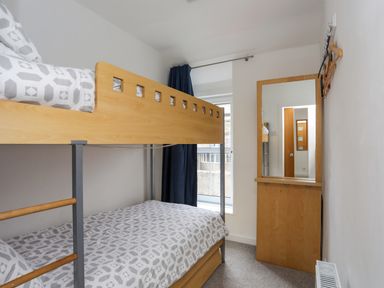 A bedroom with a wooden bunk bed and a mirror attached to the wall at Awel Y Mor in Criccieth