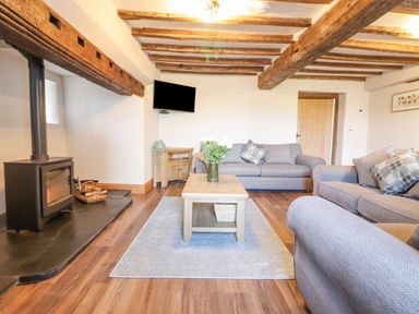 A living room with wooden beams on the ceiling sofas and a coffee table at Plas Iolyn in Pentrefoelas near Betws-Y-Coed