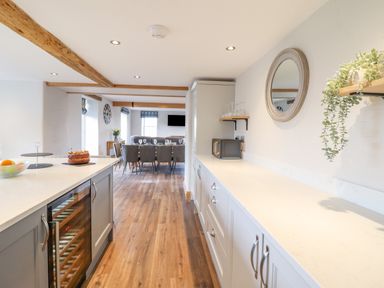 A kitchen with cabinets and a countertop extending to a dining area with a table and chairs at Plas Iolyn in Pentrefoelas near Betws-Y-Coed