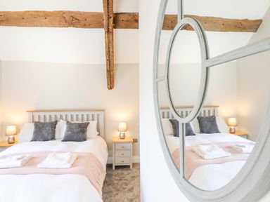 A bedroom with a bed a headboard side tables with lamps and exposed wooden beams at Plas Iolyn in Pentrefoelas near Betws-Y-Coed