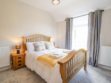 A bedroom with a wooden bed and bedside tables with lamps at Plas Iolyn in Pentrefoelas near Betws-Y-Coed