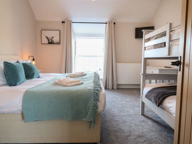 A bedroom with a double bed and bunk beds near a window at Plas Iolyn in Pentrefoelas near Betws-Y-Coed
