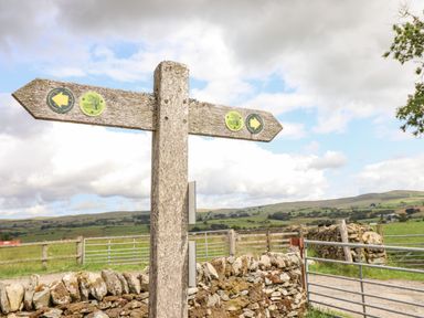A wooden signpost with arrows pointing left and right in a rural landscape with stone walls and metal gates at Plas Iolyn in Pentrefoelas near Betws-Y-Coed