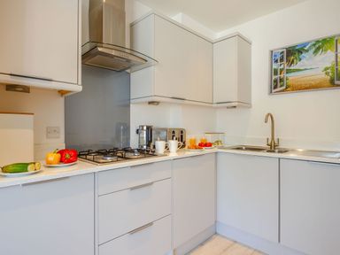 A kitchen with gas stove countertop cabinets sink and a wall art at Sea View in Llanfaelog