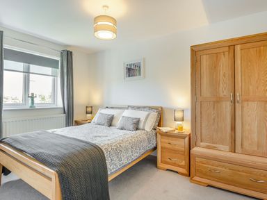 A bedroom with a wooden bed and matching bedside tables and wardrobe at Sea View in Llanfaelog