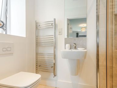 A bathroom with a wall-mounted toilet sink towel rack and a shower at Sea View in Llanfaelog