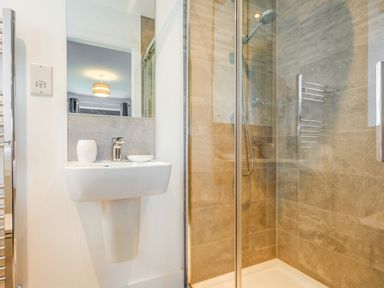 A bathroom with a wall-mounted sink and a glass-enclosed shower at Sea View in Llanfaelog