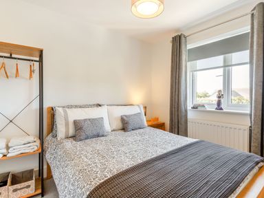 A bedroom with a bed bedside table window and open shelving at Sea View in Llanfaelog
