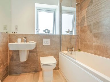 A bathroom with a toilet sink and bathtub with shower at Sea View in Llanfaelog