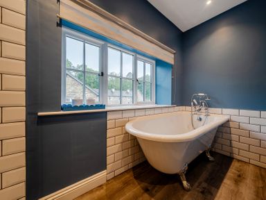 A bathroom with a bathtub and window at Home Farmhouse at the Graythwaite Estate near Hawkshead