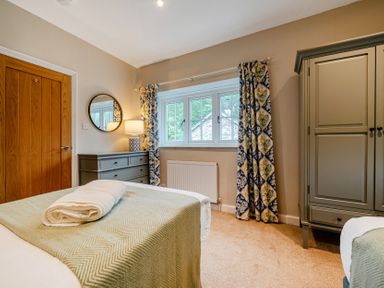 A bedroom with two beds and a dresser at Home Farmhouse at the Graythwaite Estate near Hawkshead