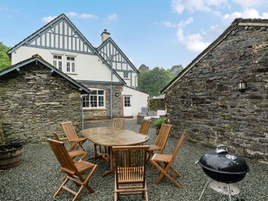 An outdoor seating area with a table and chairs at Home Farmhouse at the Graythwaite Estate near Hawkshead