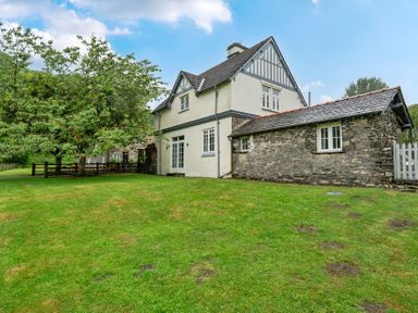 A house with a grassy area and trees at Home Farmhouse at the Graythwaite Estate near Hawkshead