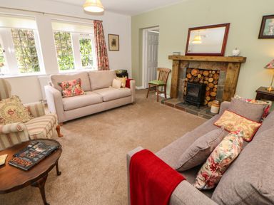 A living room with two sofas a striped armchair a wooden coffee table and a fireplace at The Coach House in Shepherd's Dene near Corbridge