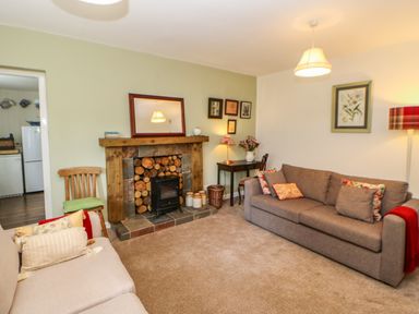 A living room with two sofas a fireplace and a small desk with a lamp at The Coach House Shepherd's Dene near Corbridge