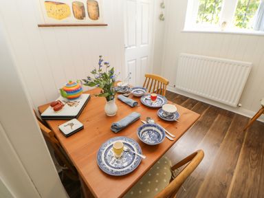 A dining table set with blue and white china and napkins in a room with wood floor at The Coach House Shepherd's Dene near Corbridge