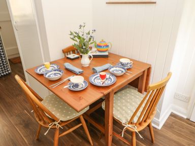 A small wooden dining table set for four with blue and white dishes and polka dot chair cushions at The Coach House in Shepherd's Dene near Corbridge