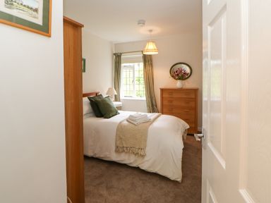 A bedroom with a bed a wooden chest of drawers and a window at The Coach House Shepherd's Dene near Corbridge