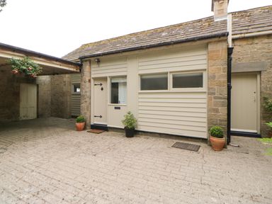 A courtyard with stone walls doors and potted plants at The Coach House in Shepherd's Dene near Corbridge