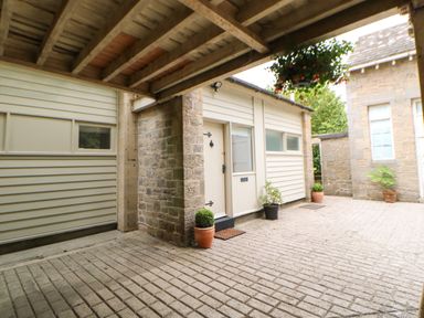 A covered outdoor area with potted plants and a door on a building at The Coach House Shepherd's Dene near Corbridge