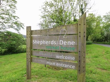 A wooden sign on a grassy area near a road with trees in the background at Shepherds Dene near Corbridge