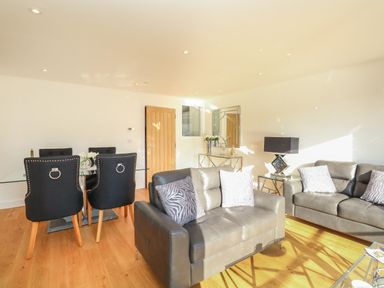 A living room with two gray sofas and a dining table with black chairs at Harbourside Haven Apartment 2 in Weymouth