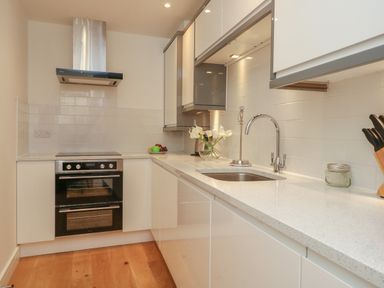 A kitchen with a stove oven a sink flowers on the counter and kitchen knives at Harbourside Haven Apartment 2 in Weymouth