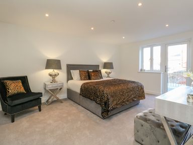 A bedroom with a bed a chair two lamps a desk and a window at Harbourside Haven Apartment 2 in Weymouth