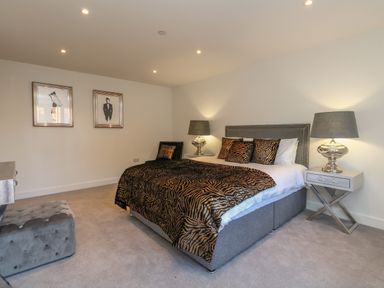 A bedroom with a double bed featuring animal print bedding two bedside tables with lamps and framed pictures on the wall at Harbourside Haven Apartment 2 in Weymouth