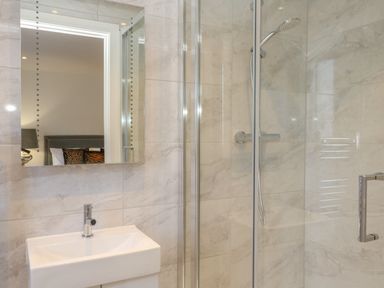A bathroom with a sink, a mirror, and a glass-enclosed shower at Harbourside Haven Apartment 2 in Weymouth
