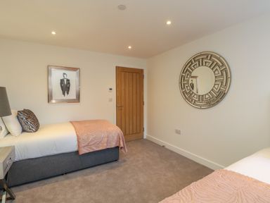 A bedroom with two single beds a wooden door a round wall mirror and a framed picture at Harbourside Haven Apartment 2 in Weymouth