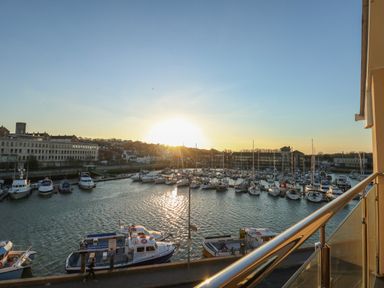 A marina with boats docked and buildings in the background at sunset at Harbourside Haven Penthouse 1 in Weymouth