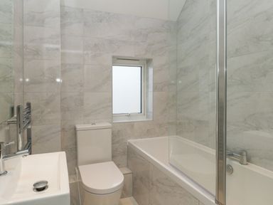 A bathroom with a toilet sink and bathtub with glass screen at Harbourside Haven Penthouse 1 in Weymouth