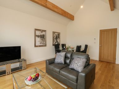 A living room with a leather sofa glass coffee table and dining table with chairs at Harbourside Haven Penthouse 2 in Weymouth