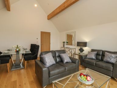 A living room with leather sofas glass coffee table and dining table with chairs at Harbourside Haven Penthouse 2 in Weymouth
