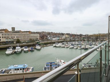 View of a marina with boats docked and buildings in the background from a balcony at Harbourside Haven Penthouse 2 in Weymouth