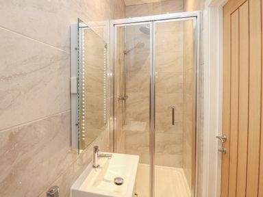 A bathroom with a glass shower enclosure a sink with faucet and a mirror at Harbourside Haven Penthouse 2 in Weymouth