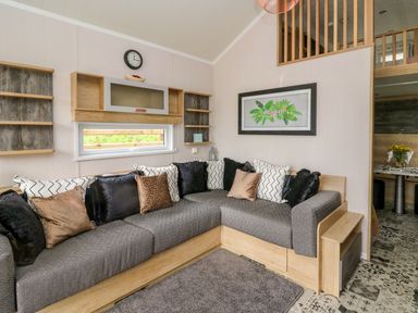 A living room with a corner sofa and decorative pillows at Woodland Escape in Rhayader