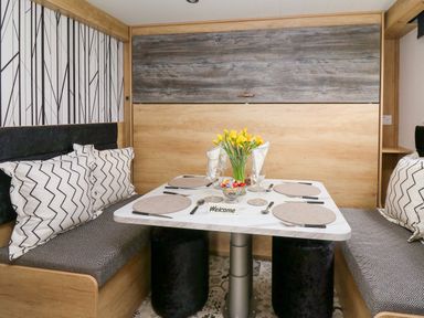 A dining area with a table set for four with cushions on bench seating at Woodland Escape in Rhayader