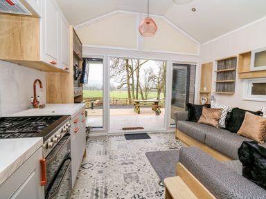A kitchen and living area with a stove sofa and sliding glass doors opening to a patio at Woodland Escape in Rhayader
