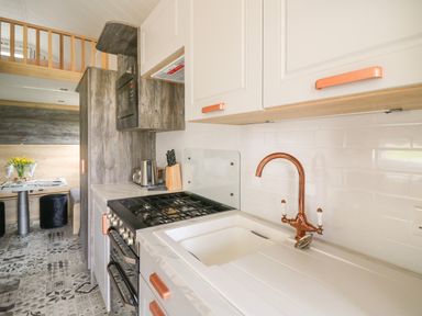 A kitchen with a stove sink and copper faucet at Woodland Escape in Rhayader