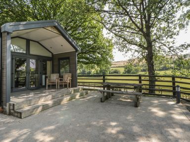 An outdoor area with wooden chairs and a table at Woodland Escape in Rhayader