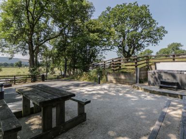 An outdoor area with a table and bench at Woodland Escape in Rhayader