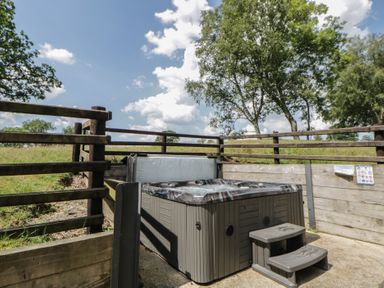 A hot tub with steps in a fenced outdoor area at Woodland Escape Rhayader